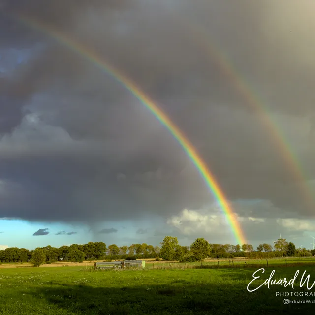 Dubbele regenboog boven de wei
